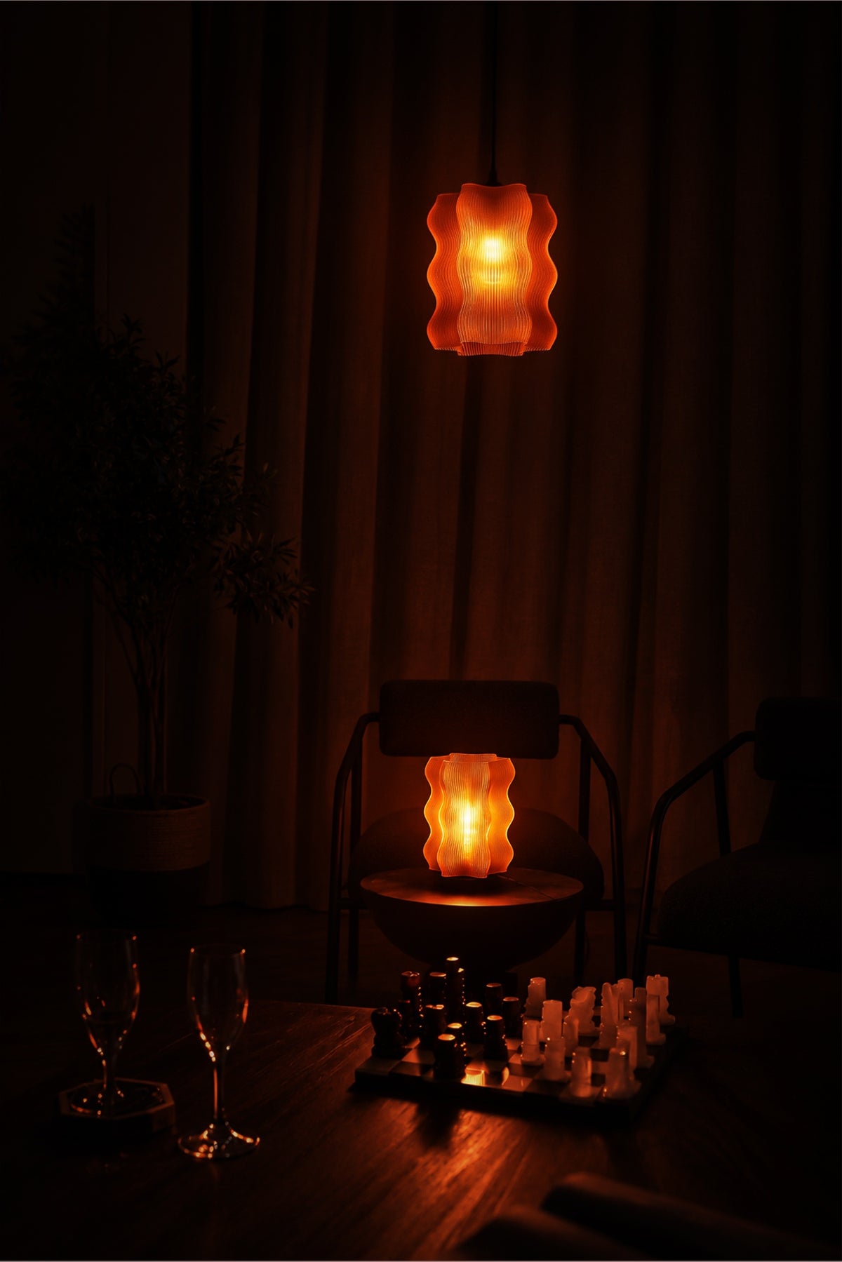 A dimly lit room features two Reef Pendant lights from My Store casting an atmospheric glow; a chessboard is set in the foreground while empty chairs and glasses contribute to the quiet ambiance.