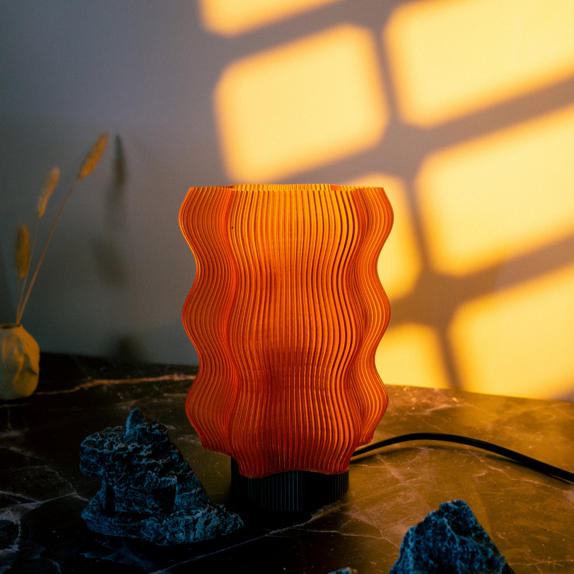 Amber mood lighting table lamp for cosy spaces

Reef Table Lamp (Seconds) by OrijaDesign sits on a dark marble surface, casting warm coral reef-inspired shadows on the wall, with decor objects nearby.

