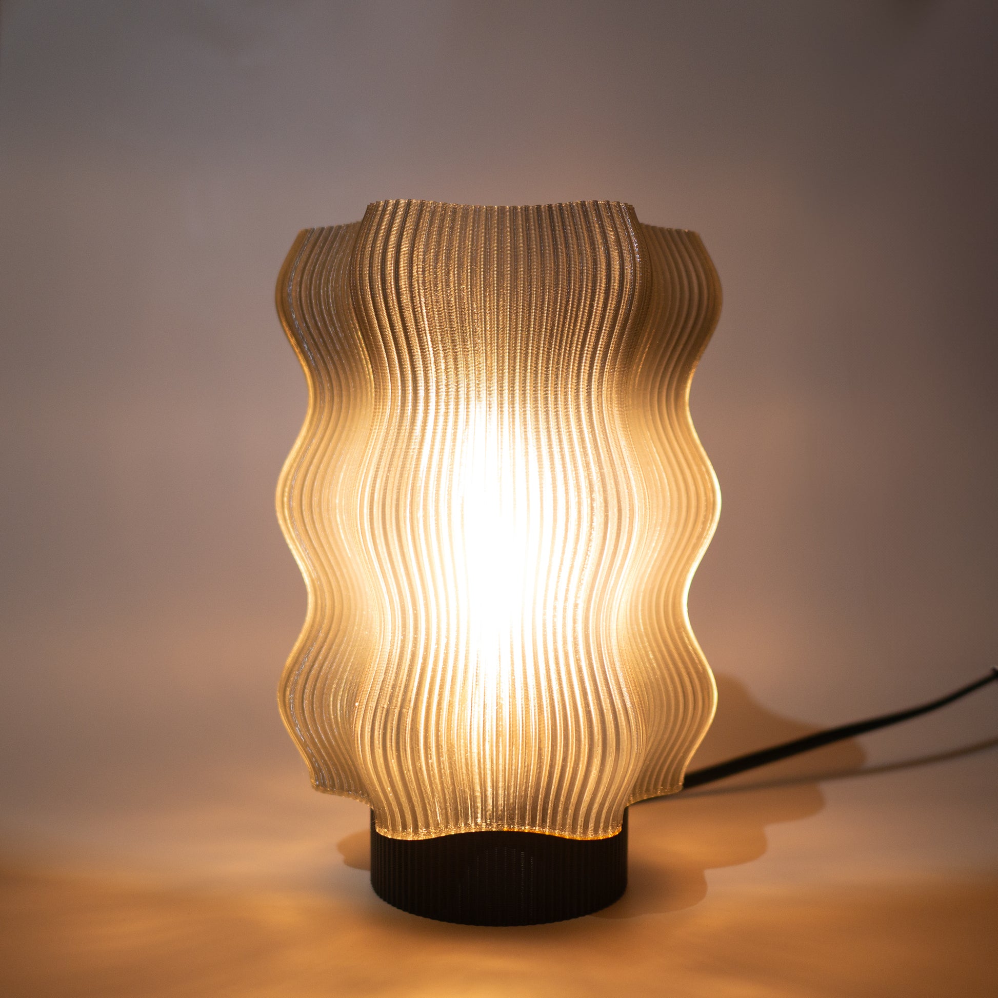 The Reef Table Lamp by OrijaDesign features a wavy, translucent shade inspired by coral reefs. Its soft, warm light and visible power cord bring a modern ocean decor touch to any flat surface.