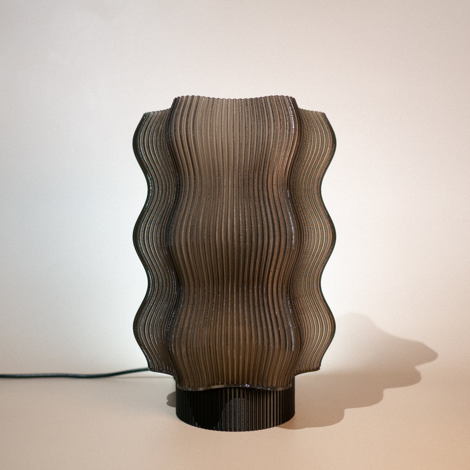 The Reef Table Lamp (Seconds) by OrijaDesign features a sculptural design with a wavy, ribbed brown shade and black base, evoking coral reefs—ideal for adding subtle, modern elegance to your decor.
